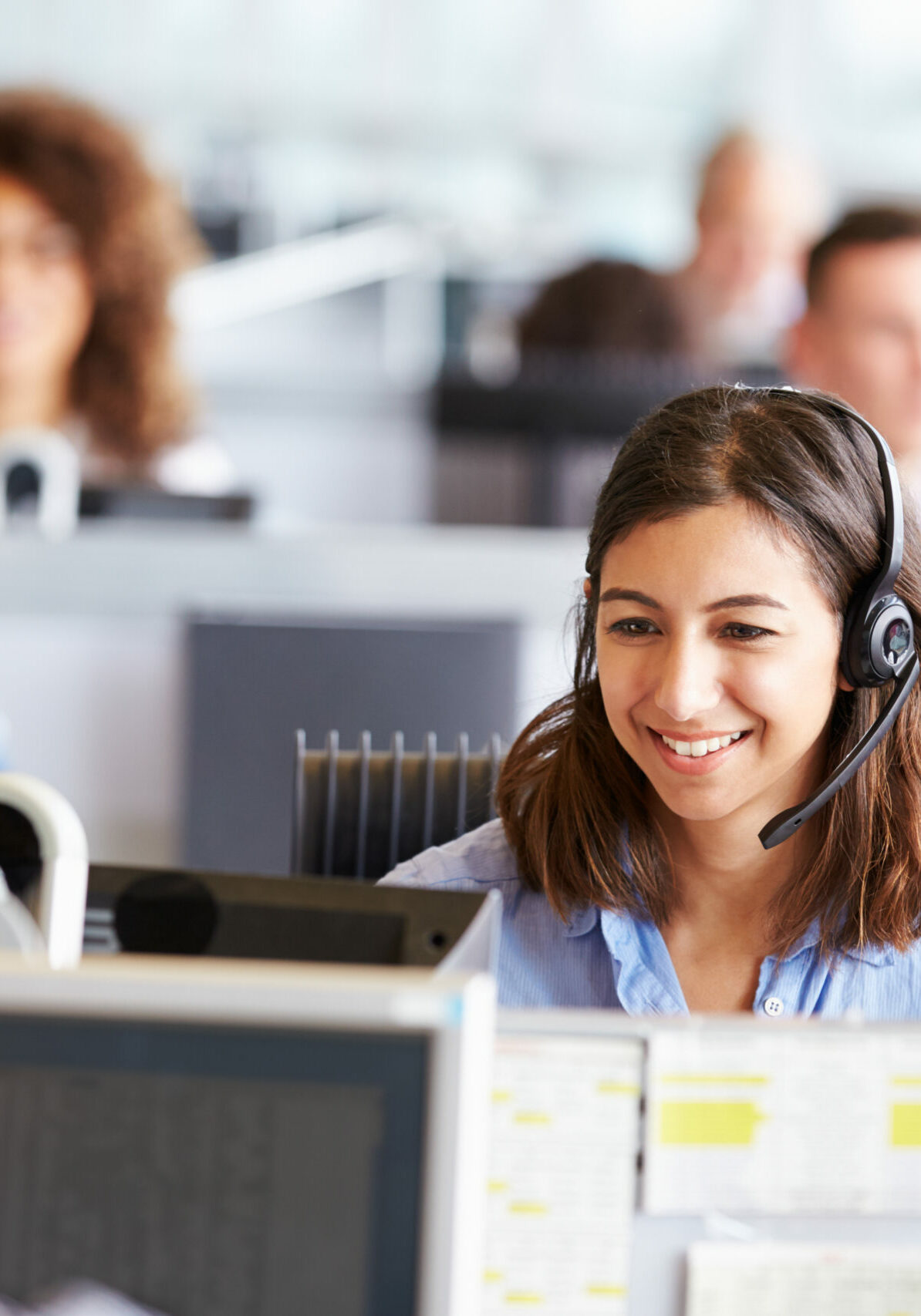 Young woman working in call centre, surrounded by colleagues